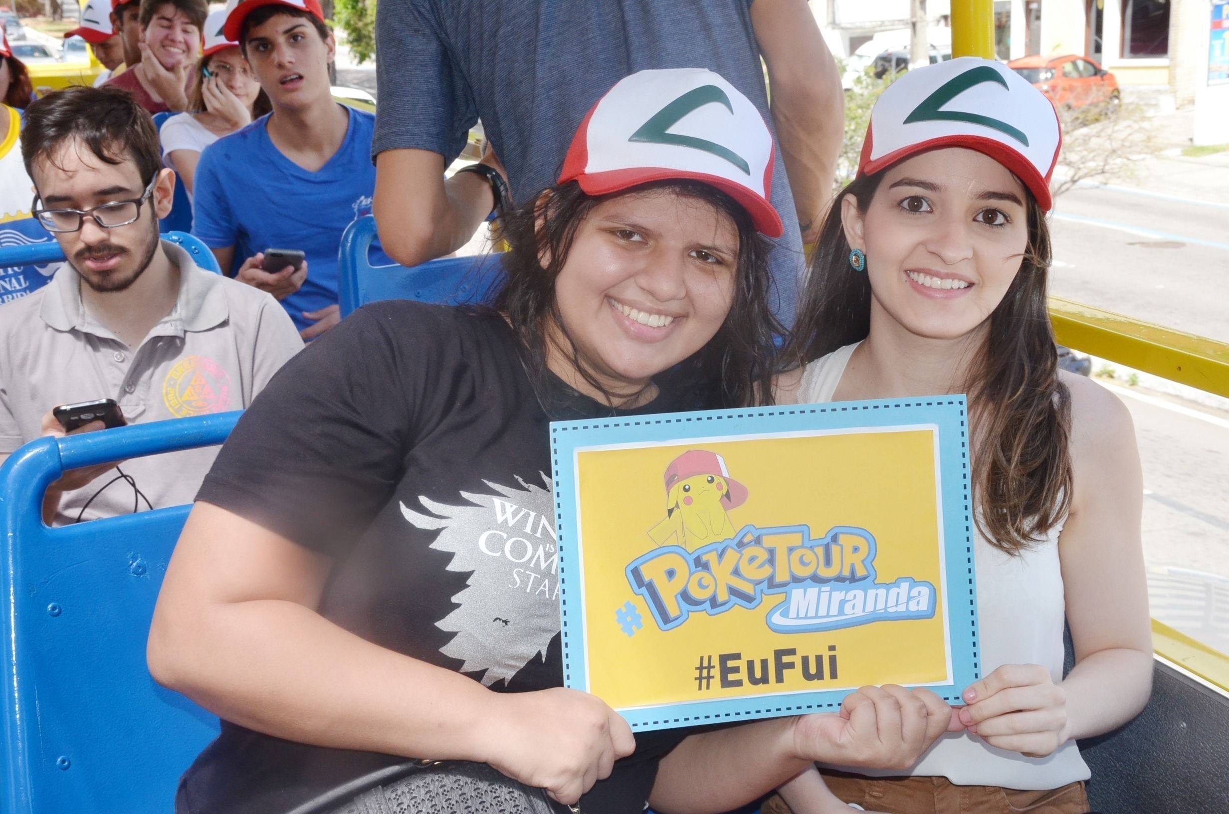 Duas meninas sentadas no ônibus com a placa da poketur